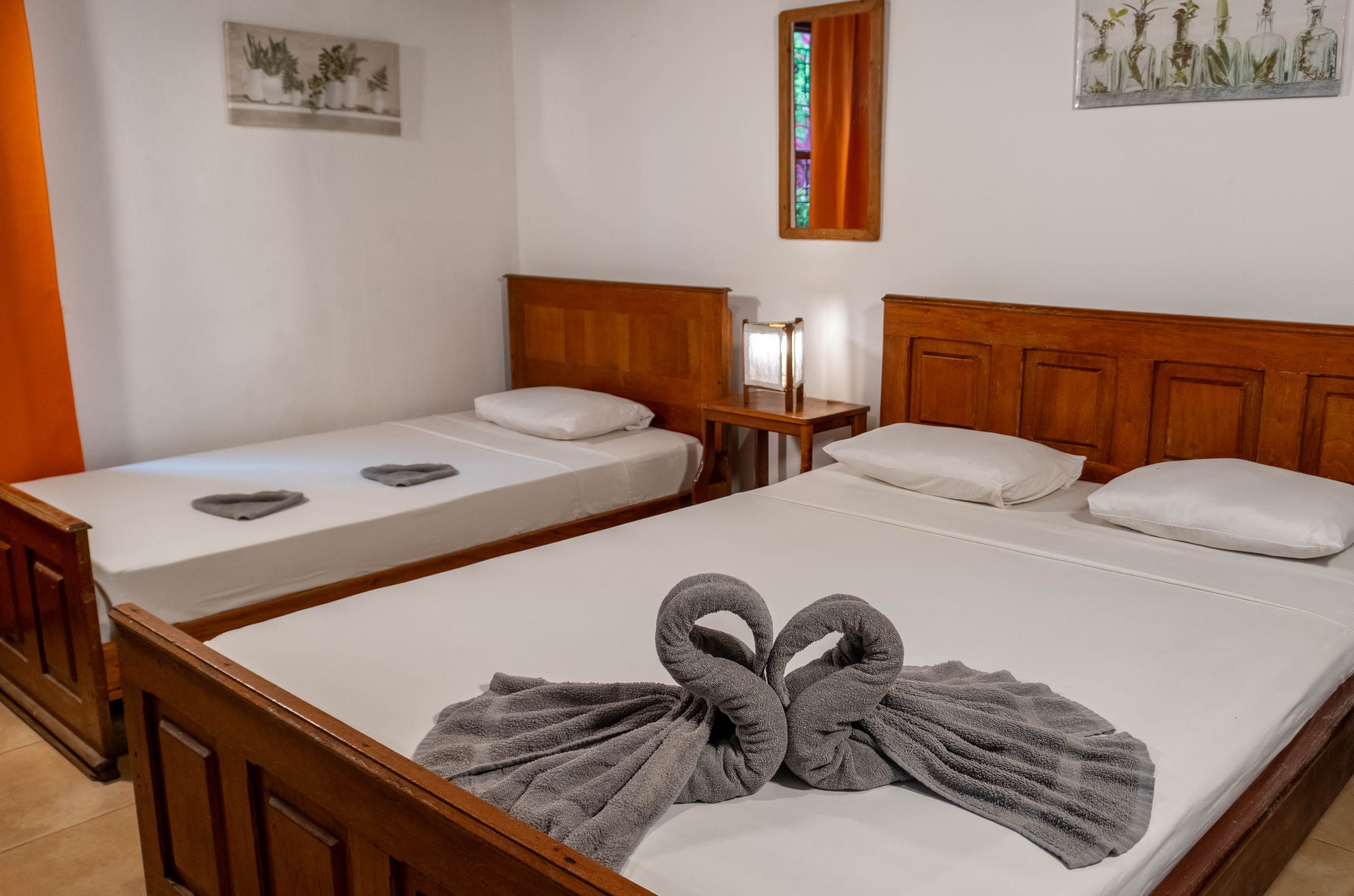 Jardín room bed with a wood headboard beneath framed parrot and toucan artwork, lit by a bedside lamp with fresh flowers